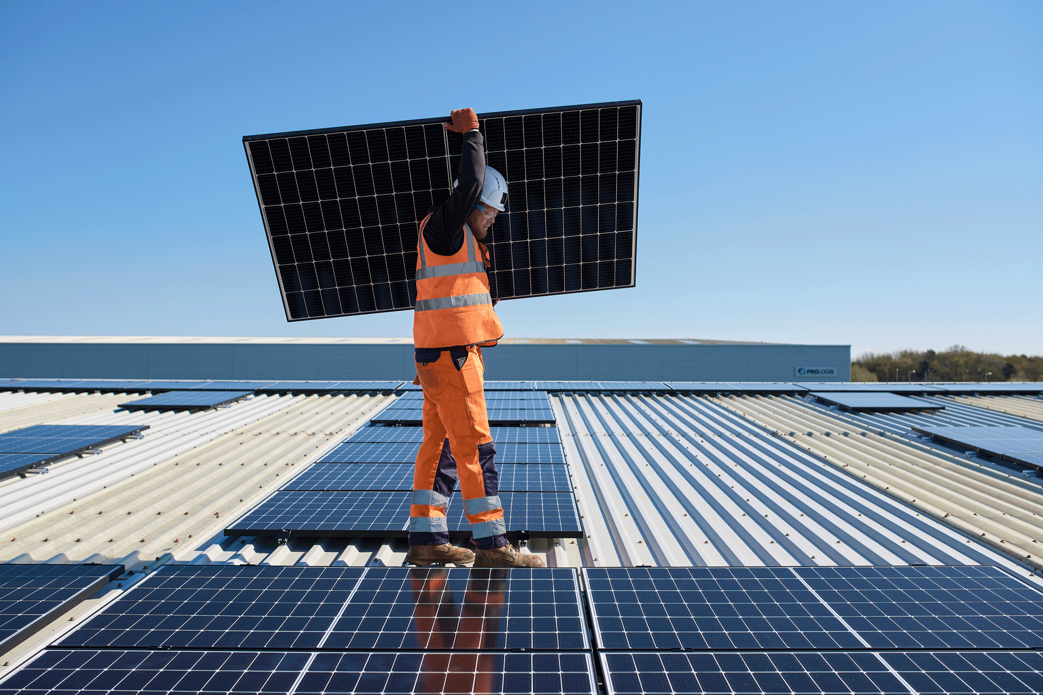 Person trägt ein Solarmodul auf einem Dach